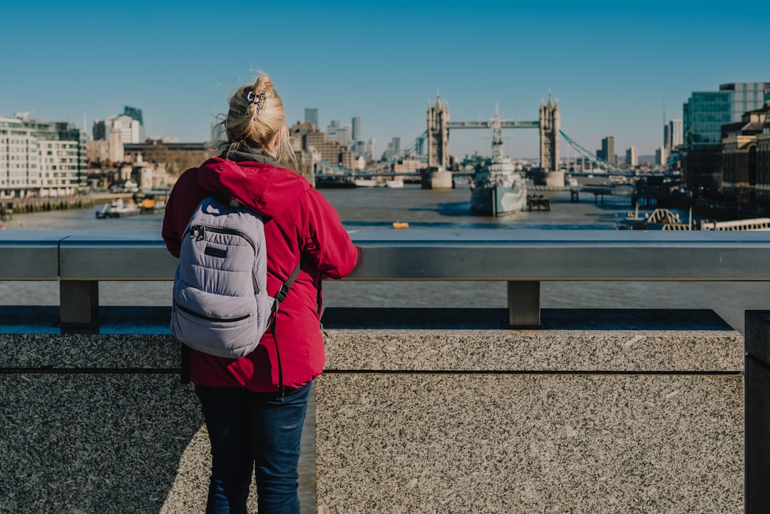 Femme voyageuse seule avec sac à dos contemplant un panorama urbain depuis un pont